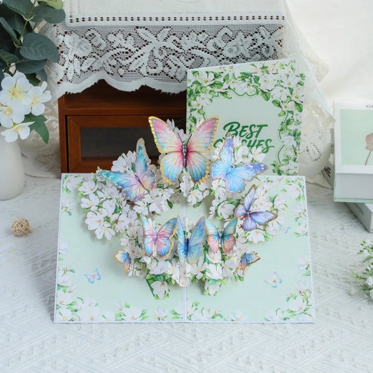 3D pop-up greeting card featuring colorful butterflies and white flowers with Best Wishes text on cover