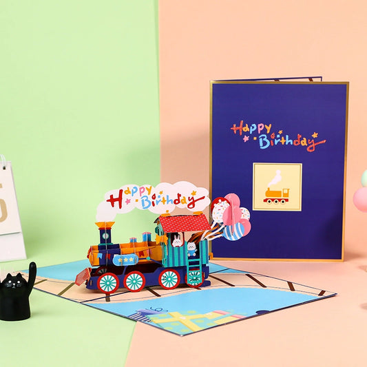 3D pop-up birthday card featuring a colorful steam train with "Happy Birthday" smoke, cute bunnies, and balloons