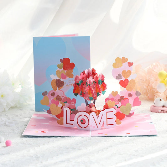 Open flat view of love pop-up card displaying intricate paper cutting details and pastel pink background