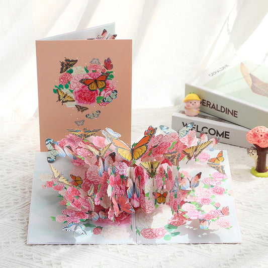 Closed view of the 3D pop-up card featuring an artistic illustration of pink flowers and butterflies on a peach background.