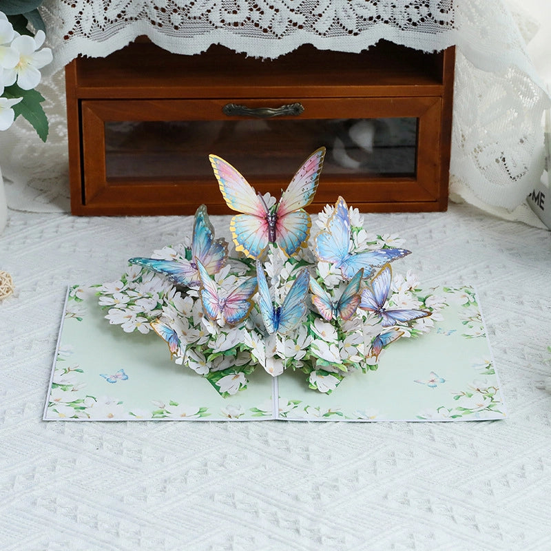Close-up of intricate paper cut butterflies in blue, pink, and yellow resting on white floral bouquet