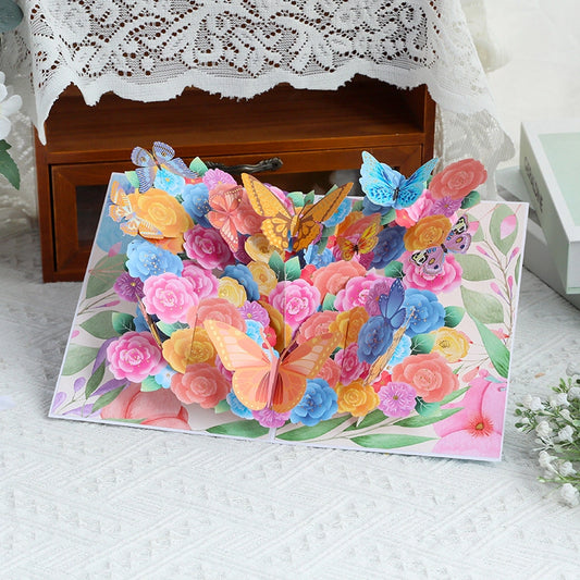 Front view of colorful butterfly garden greeting card open on white lace tablecloth