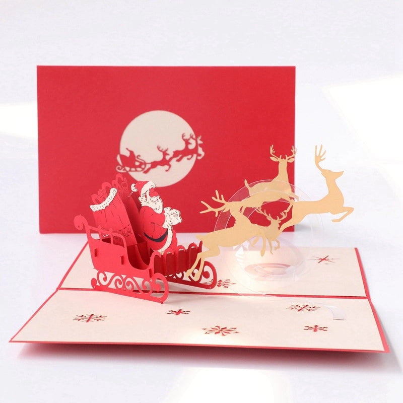 Close-up detail of a handmade 3D Christmas card showing intricate red snowflake patterns and a detailed paper-cut Santa sleigh.