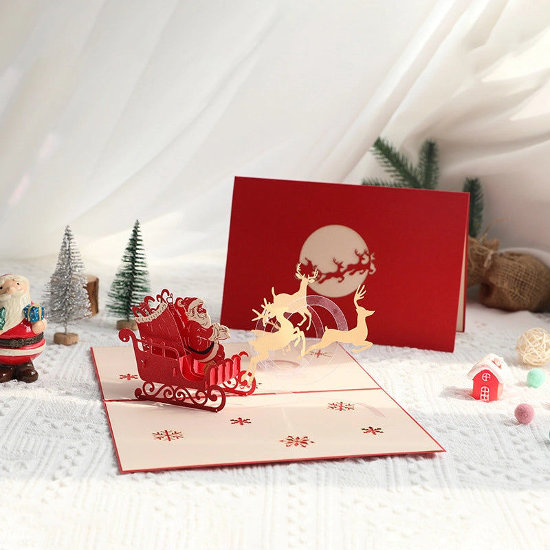 Premium 3D pop-up Santa card displayed as a holiday gift idea, set on a cozy white knitted surface with festive decorations.