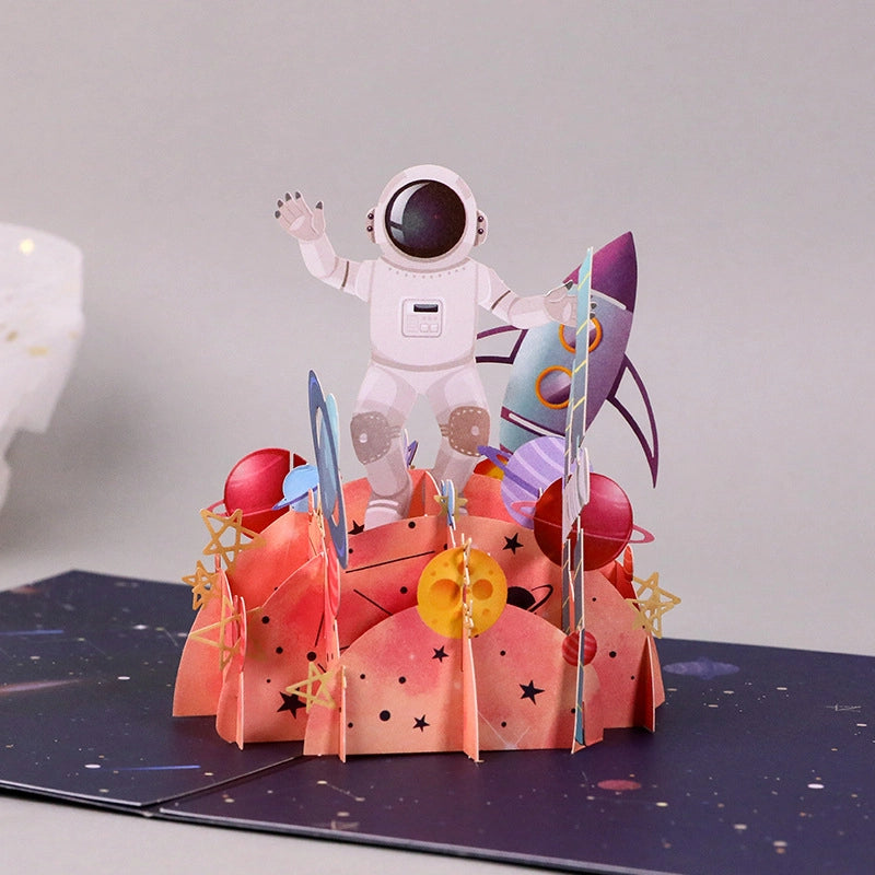 Detailed 3D pop-up astronaut greeting card with rocket, planets and colorful space adventure decorations