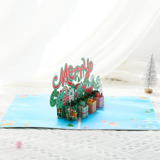 Side view of the festive 3D greeting card highlighting the layered paper art of the Christmas text and presents on a blue background.