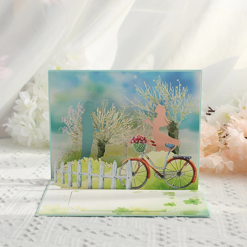 Open 3D romantic card showing a detailed paper-cut scene of a bicycle, white fence, and lovers silhouette in a garden.