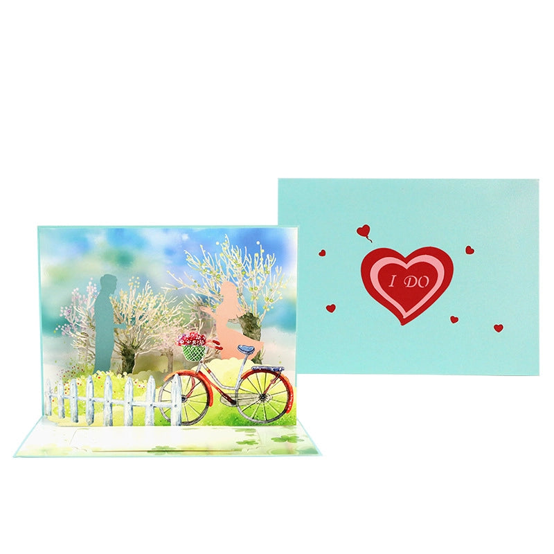 Comparison view of the closed "I Do" wedding card cover and the open 3D bicycle pop-up interior.