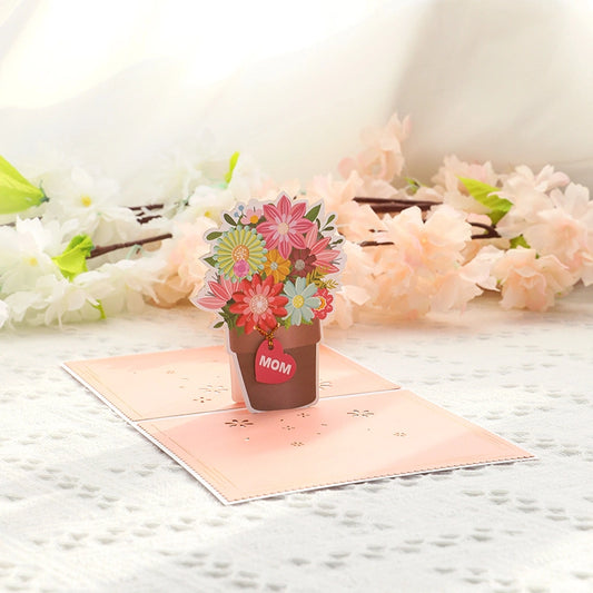 Close up of 3D paper craft flower pot with hanging red heart tag saying MOM for Mother's Day gift
