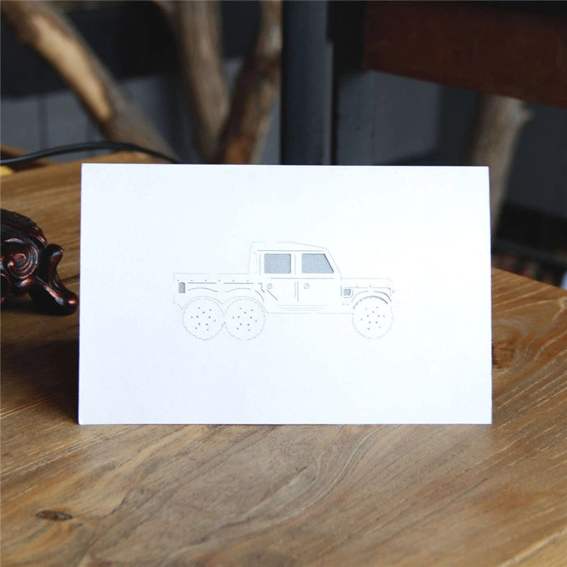 Front cover of the greeting card featuring a minimalist grey outline sketch of a six-wheeled pickup truck on white paper.