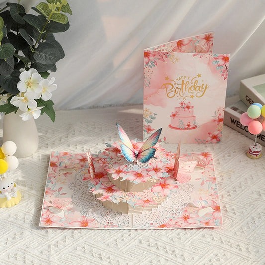 Pink 3D pop-up birthday card featuring butterflies and flowers on a white textured table