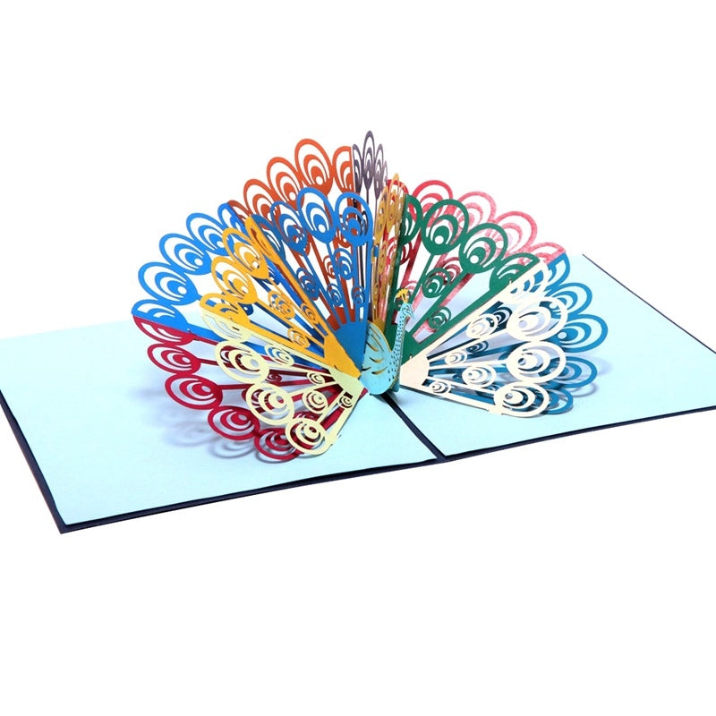 Side angle view showing the depth and layering of the multi-colored paper peacock tail