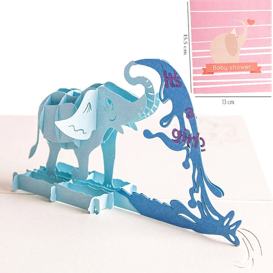 Blue 3D pop-up card opened to reveal a standing paper elephant spraying water with text "It's a girl", size 13x15.5cm
