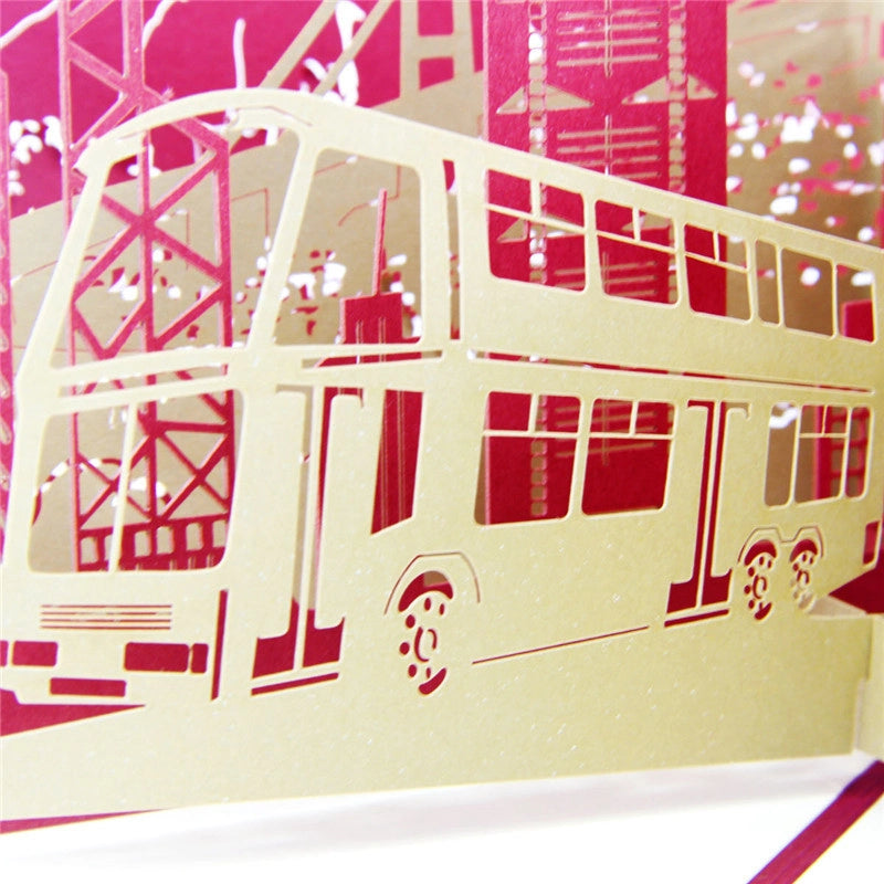 Close-up detail of intricate gold paper cut double-decker bus on Hong Kong themed 3D greeting card
