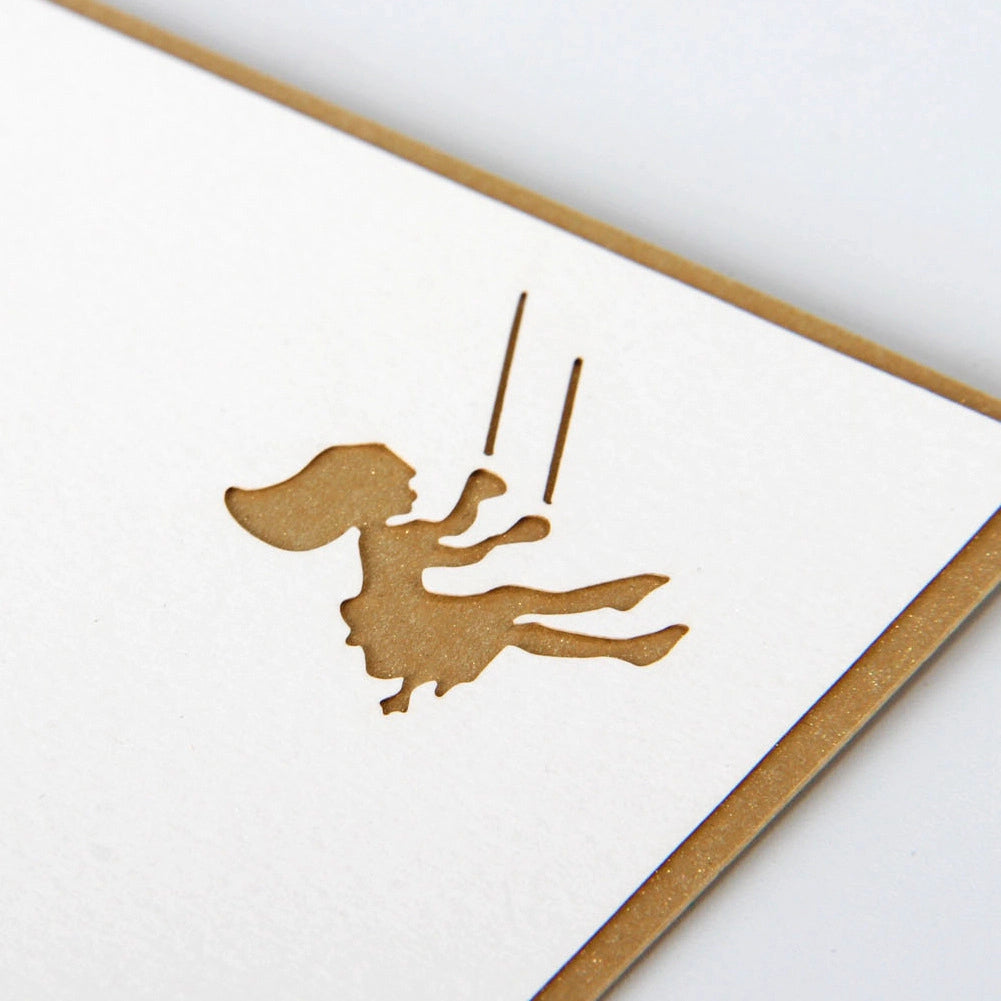 Gold foil stamped detail of swinging girl silhouette on white inner panel of greeting card
