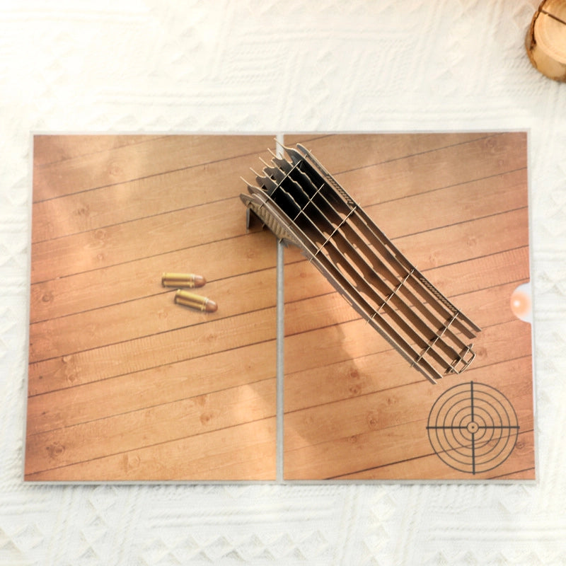 Inside view of the pop-up card showing a printed wooden floor scene with bullet illustrations and a target design on the bottom right
