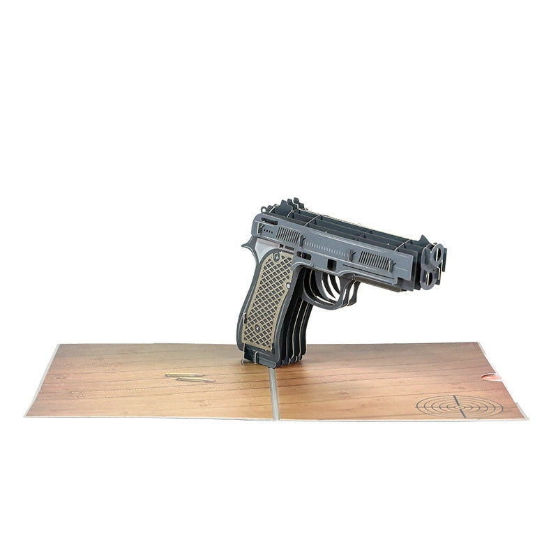 Isolated view of the 3D paper pistol pop-up card against a white background, highlighting the structural layers of the handmade craft
