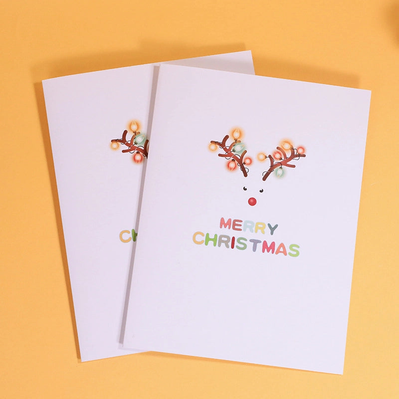 White Christmas card cover with minimalist reindeer antler lights design and Merry Christmas text.